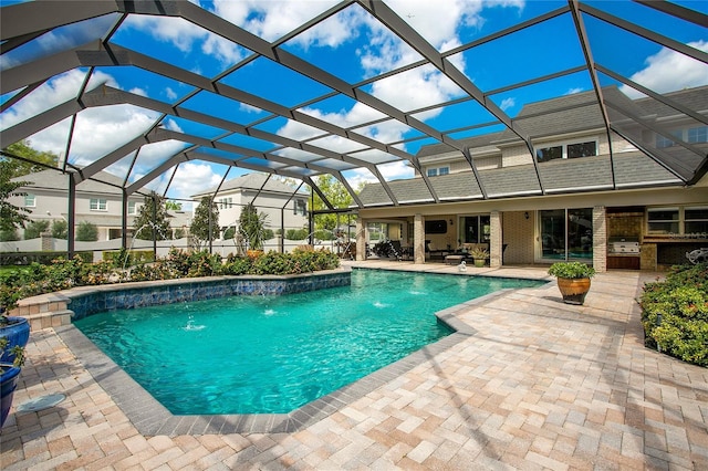 view of swimming pool featuring exterior kitchen, a patio, pool water feature, and a lanai