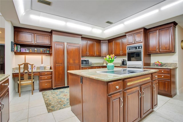 kitchen with oven, a center island, black electric stovetop, paneled built in fridge, and light tile patterned floors