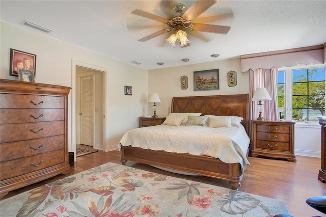 bedroom with ceiling fan, a textured ceiling, and light wood-type flooring