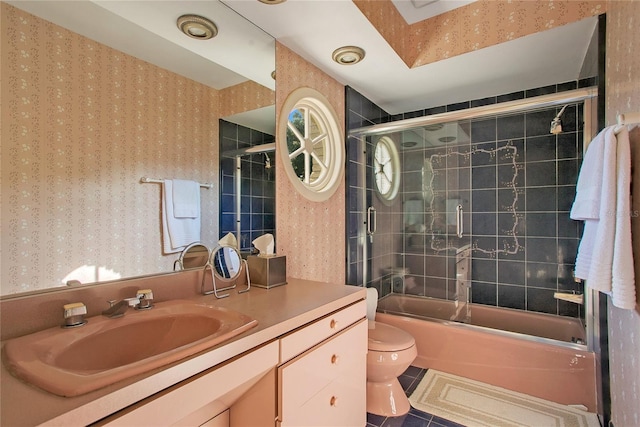 full bathroom featuring tile patterned flooring, vanity, combined bath / shower with glass door, and toilet