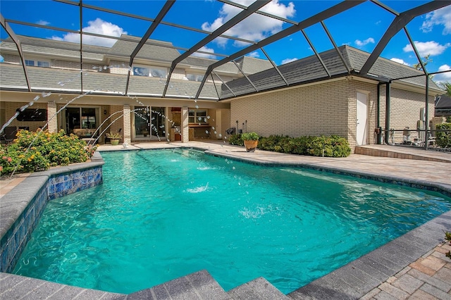 view of pool featuring a patio area, pool water feature, and glass enclosure