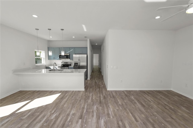 kitchen with stainless steel appliances, hanging light fixtures, hardwood / wood-style floors, and kitchen peninsula