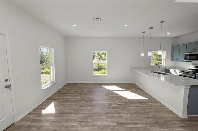 kitchen featuring appliances with stainless steel finishes, decorative light fixtures, sink, a kitchen breakfast bar, and kitchen peninsula