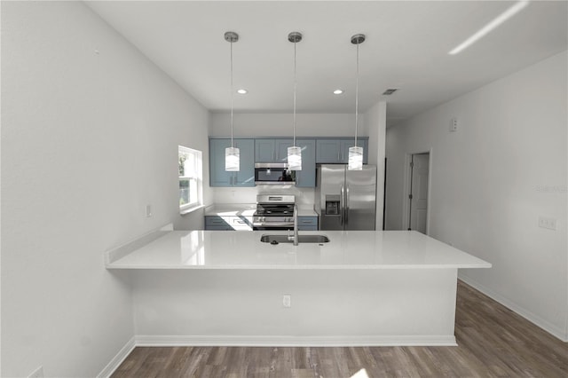 kitchen featuring stainless steel appliances, hanging light fixtures, dark wood-type flooring, and kitchen peninsula