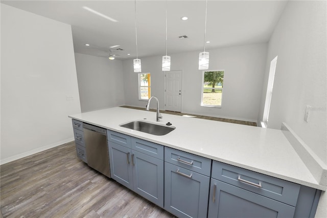 kitchen with sink, hardwood / wood-style floors, light stone countertops, decorative light fixtures, and stainless steel dishwasher