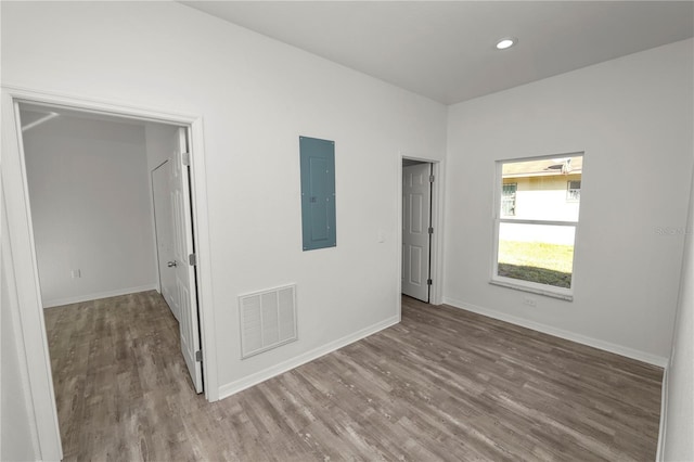 empty room with electric panel and hardwood / wood-style floors