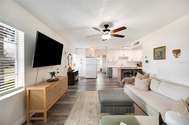 living room with dark wood-type flooring, ceiling fan, and sink