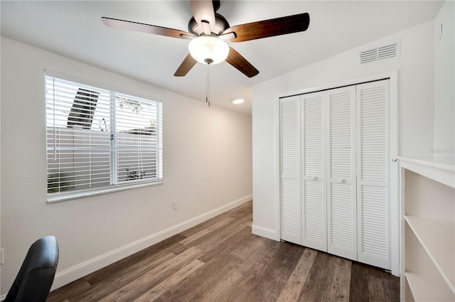 unfurnished bedroom with dark wood-type flooring, a closet, and ceiling fan