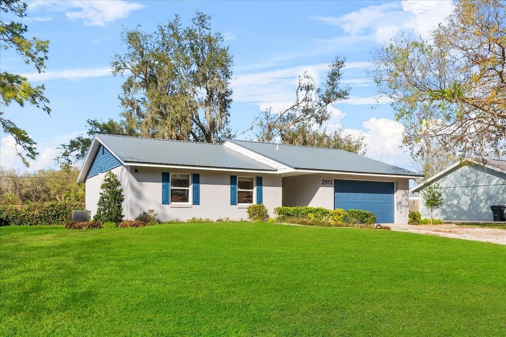 single story home with central AC unit, a garage, and a front yard