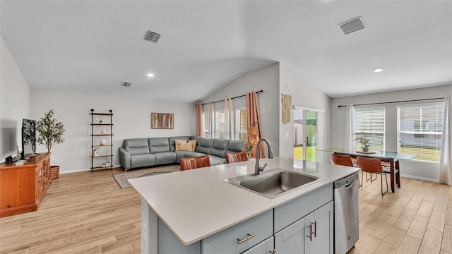 kitchen featuring lofted ceiling, sink, light wood-type flooring, stainless steel dishwasher, and a kitchen island with sink