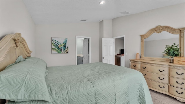 bedroom featuring lofted ceiling, ensuite bath, and light carpet