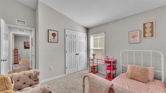 bedroom featuring vaulted ceiling, light colored carpet, a closet, and a textured ceiling