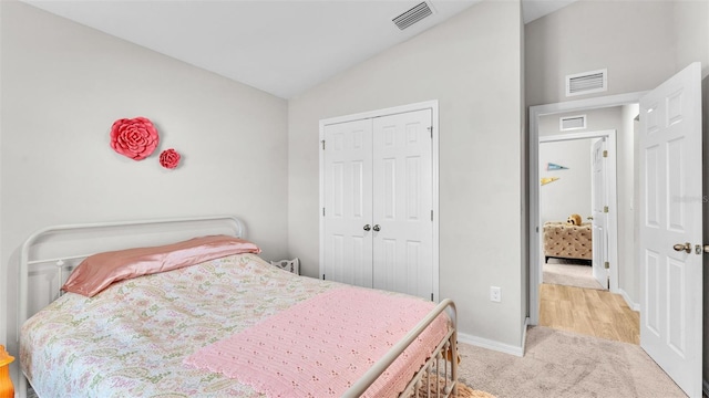 bedroom with vaulted ceiling, light carpet, and a closet