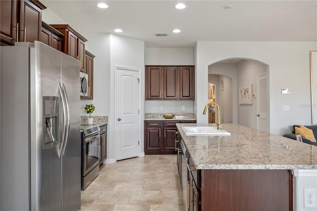 kitchen with stainless steel appliances, dark brown cabinets, and sink