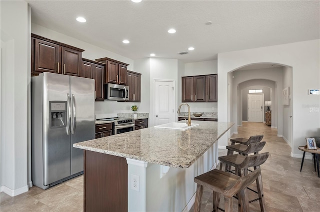 kitchen with an island with sink, appliances with stainless steel finishes, a breakfast bar, and sink