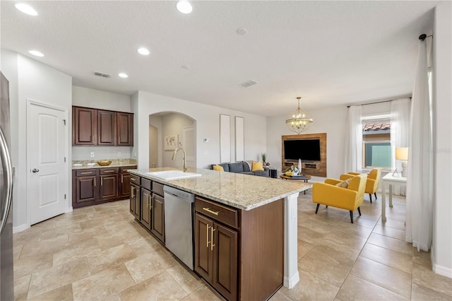 kitchen with sink, dark brown cabinetry, an island with sink, decorative light fixtures, and stainless steel dishwasher