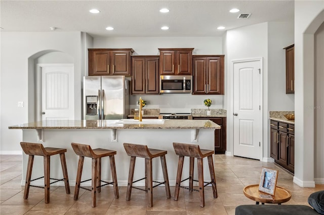 kitchen with stainless steel appliances, a kitchen island with sink, and a breakfast bar