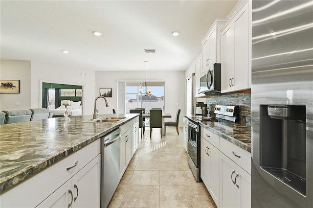 kitchen with sink, decorative light fixtures, dark stone countertops, appliances with stainless steel finishes, and white cabinets