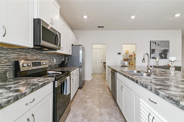 kitchen featuring tasteful backsplash, white cabinetry, sink, dark stone counters, and stainless steel appliances