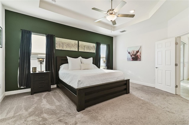 bedroom with a raised ceiling, ceiling fan, and carpet flooring