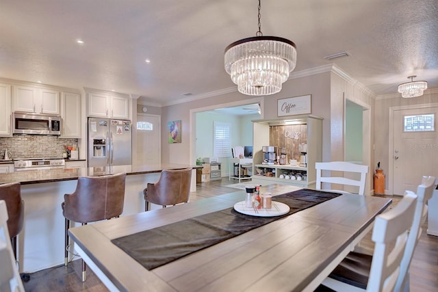 dining space featuring crown molding, dark hardwood / wood-style flooring, and an inviting chandelier