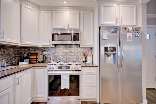 kitchen featuring white cabinetry, stainless steel appliances, tasteful backsplash, and dark stone countertops