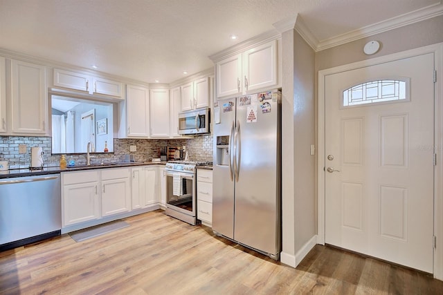 kitchen with stainless steel appliances, white cabinets, and light hardwood / wood-style flooring