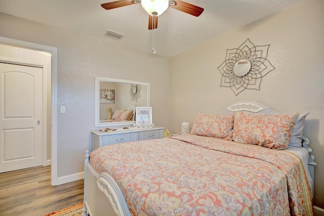 bedroom with hardwood / wood-style flooring, ceiling fan, and a textured ceiling