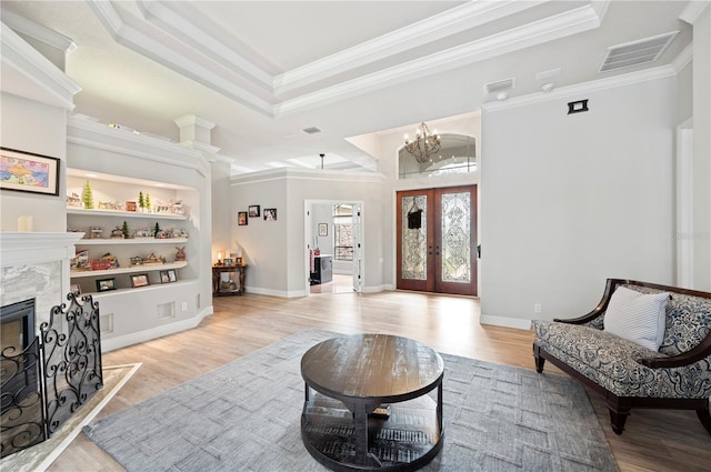 living area with crown molding, a high end fireplace, and light hardwood / wood-style floors