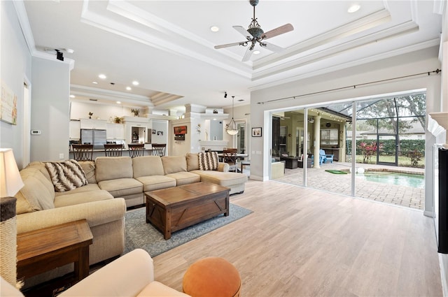 living room featuring a raised ceiling, ornamental molding, ceiling fan, and light hardwood / wood-style floors