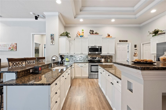 kitchen featuring stainless steel appliances, sink, dark stone countertops, and kitchen peninsula