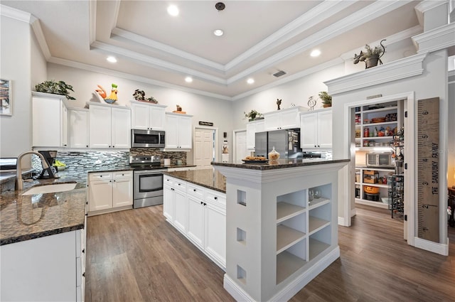 kitchen with a kitchen island, appliances with stainless steel finishes, white cabinets, and dark stone counters