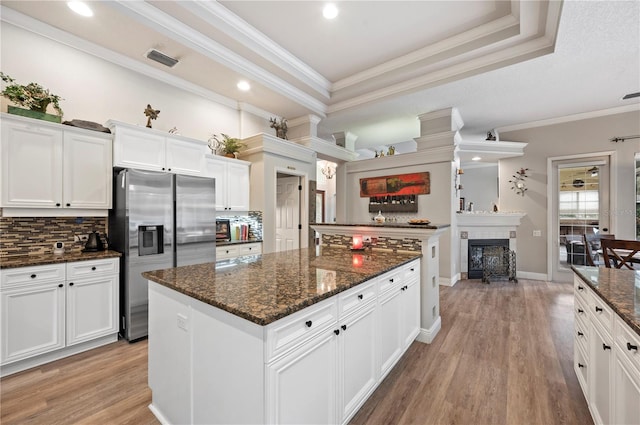 kitchen featuring a kitchen island, white cabinets, dark stone counters, and stainless steel fridge with ice dispenser