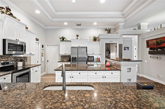 kitchen with white cabinets, stainless steel appliances, sink, and dark stone counters