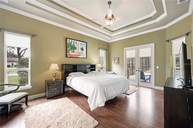 bedroom featuring dark hardwood / wood-style flooring, ornamental molding, access to exterior, a tray ceiling, and french doors