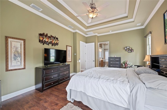 bedroom with connected bathroom, ornamental molding, a tray ceiling, dark hardwood / wood-style flooring, and ceiling fan