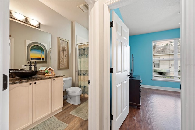 bathroom featuring toilet, a shower with curtain, a textured ceiling, vanity, and hardwood / wood-style floors