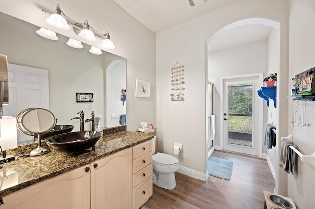 bathroom with wood-type flooring, a shower with shower door, vanity, and toilet