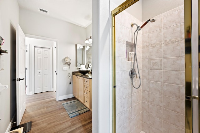 bathroom featuring hardwood / wood-style floors, vanity, and a tile shower