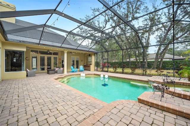 view of pool with french doors, pool water feature, a lanai, ceiling fan, and a patio