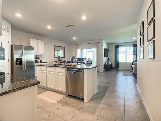 kitchen featuring visible vents, appliances with stainless steel finishes, light tile patterned flooring, white cabinetry, and a sink