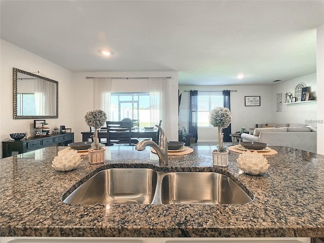 kitchen featuring dark stone countertops, recessed lighting, open floor plan, and a sink