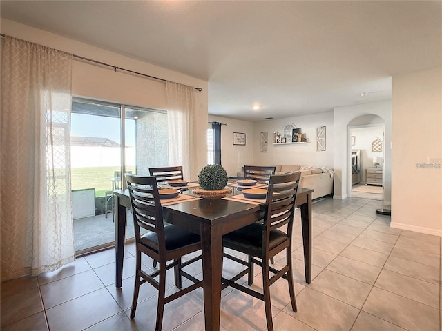 dining area with arched walkways, light tile patterned floors, and baseboards