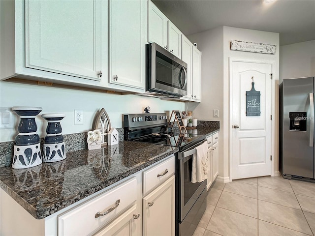 kitchen featuring white cabinetry, dark stone counters, light tile patterned flooring, and stainless steel appliances