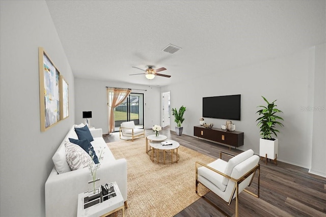 living room with ceiling fan, dark hardwood / wood-style flooring, and a textured ceiling