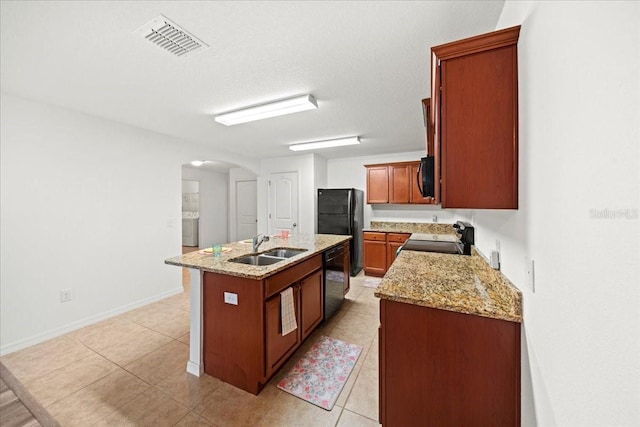 kitchen featuring sink, light stone counters, light tile patterned floors, an island with sink, and black appliances