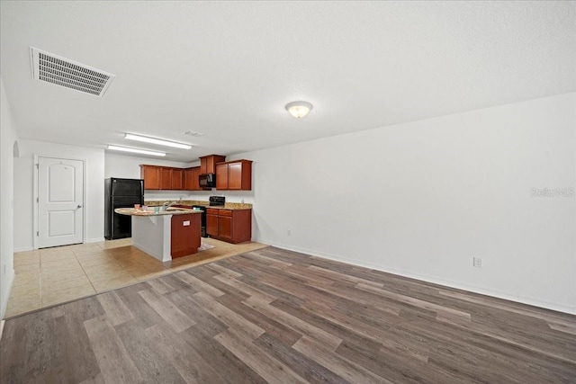 kitchen with a center island, light hardwood / wood-style flooring, and black appliances