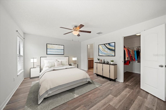 bedroom featuring wood-type flooring, a spacious closet, ceiling fan, a textured ceiling, and a closet