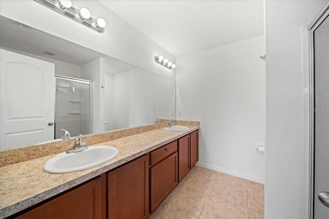 bathroom with tile patterned flooring, vanity, a textured ceiling, and walk in shower