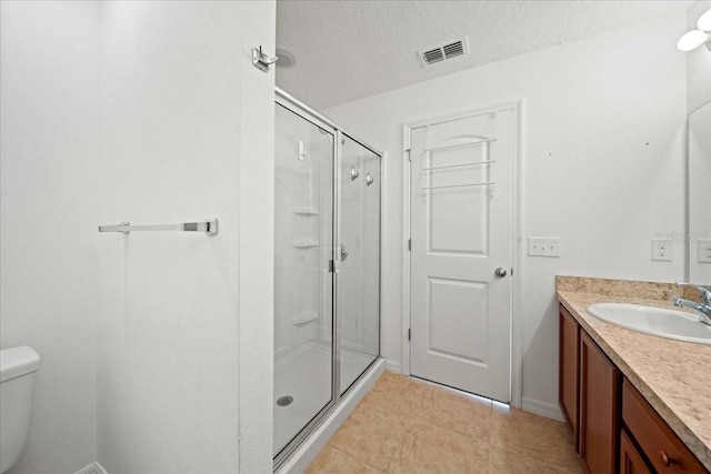 bathroom with vanity, a textured ceiling, a shower with door, and toilet